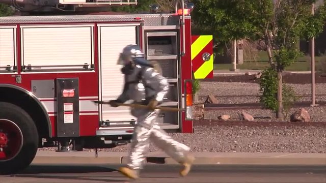 Firemen in Hazmat suits fight a simulated vehicle fire.
