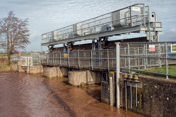 Flood Gates On Road Bridge. Swollen River In Flooded Area