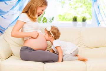 happy family. Pregnant mother and baby daughter kissing relaxing