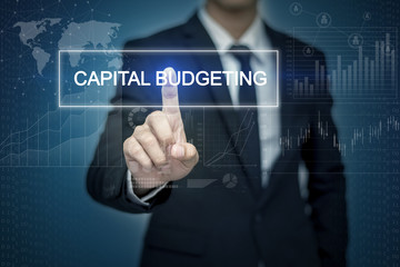 Businessman hand touching CAPITAL BUDGETING   button on virtual