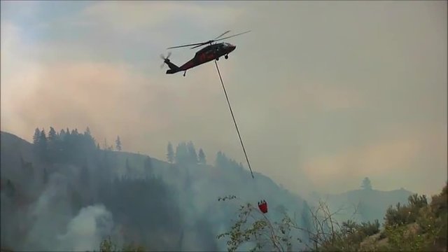 A firefighting helicopter makes airdrops on a wildfire.