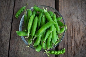 Fresh, young, unpeeled green peas in a glass plate