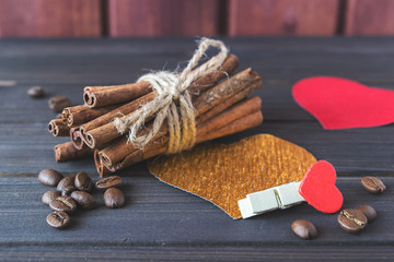 Cinnamon sticks with roasted coffee beans decorated with hearts and cloth pin on wooden planks St.Valentine's  toned selective focus
