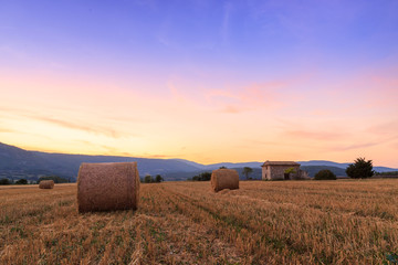Sunset over farm field with hay bales near Sault