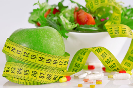 Diet concept - green apples, lettuce, pills and  measure tape