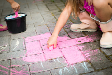 little girl drawing with pink chalk