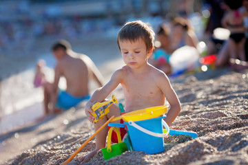 Cute little preschooler boy, playing in the sand on the beach wi