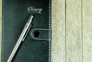 Diary notepad and pen on wood background, vintage