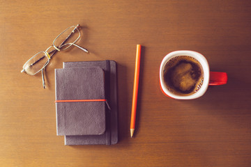Cup of coffee, notepads with glasses and pen
