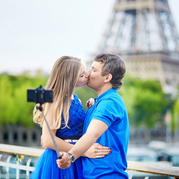 Couple in Paris making selfie using selfie stick near the Eiffel tower