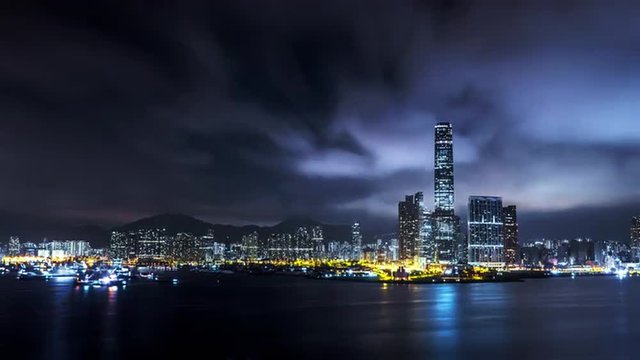 Night Hong Kong city skyline reflects in water of harbour. 4K urban background