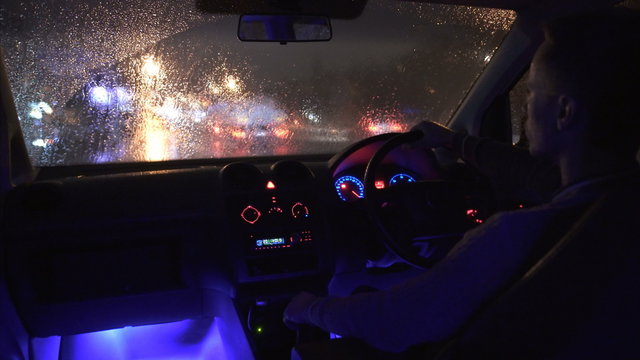 3 in 1 video! The man sit in a car in the rainy city with left hand traffic. Inside view. Evening-night time, real time capture. Wide angle