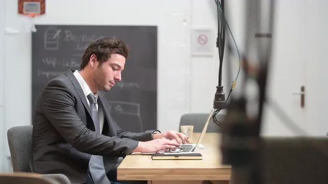 A young businessman working on his laptop in cowerking office