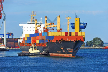 Tugboat assisting container cargo ship