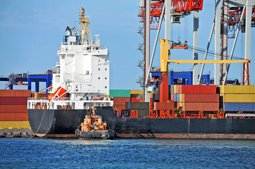 Tugboat assisting container cargo ship