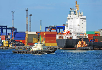 Tugboat assisting container cargo ship