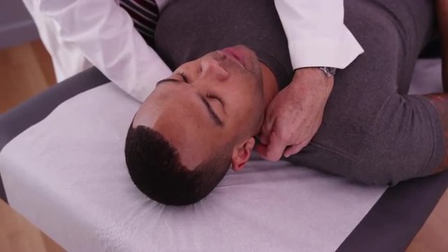 African-american male patient having neck pain examined by chiropractor