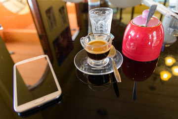 Hot espresso coffee with sugar jar and mobile phone