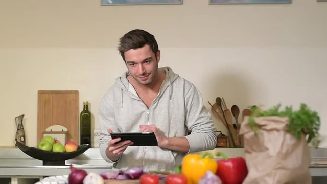 Young man cooking in kitchen at home with tablet