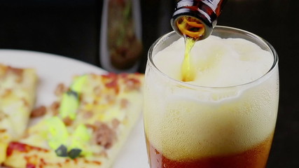 filling a glass of fresh beer with foam in front of italian pizza background, beverage and relax concept