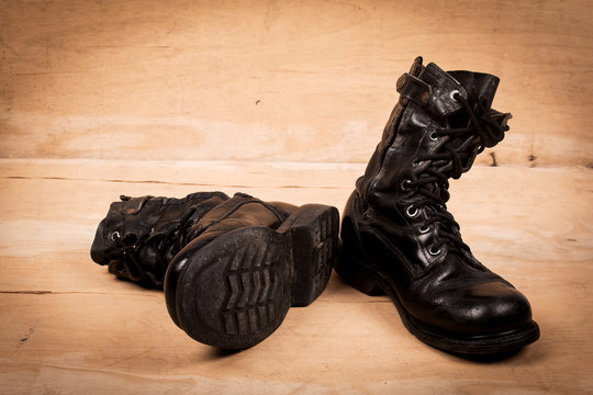 Old Black Combat Boots On Wooden Background