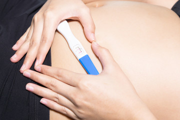 Woman hand shaped heart holding pregnancy test