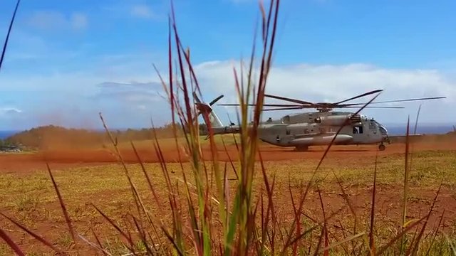 The Sikorsky CH-53 helicopter in action taking off from a field.