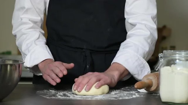 Pair of hands kneading dough on wooden table