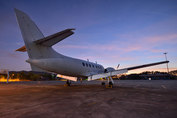 Small aeroplane infront of aircraft hangar during sunrise