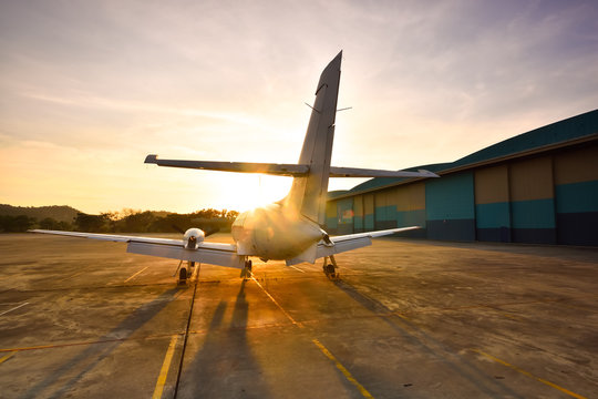 Small aeroplane infront of aircraft hangar during sunrise
