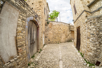 Fototapeta na wymiar Fisheye view on vanishing medieval narrow pavement street passage with stonemasonry building. Pano Lefkara, Cyprus. 