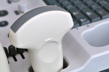 Convex abdominal ultrasound probe placed in stand of modern stationary USG machine