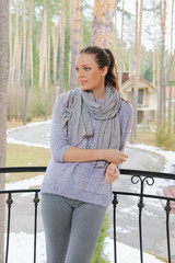 attractive lady in sweater and scarf standing on balcony