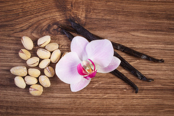 Fototapeta na wymiar Pistachio nuts, blooming orchid and fragrant vanilla sticks, cosmetic ingredients