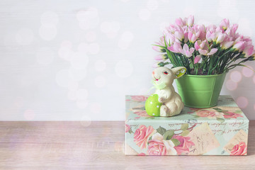 Easter bunny with egg, pink snowdrops in a pot and green box on