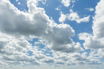 White cumulus clouds in azure sunny sky with sun backlight