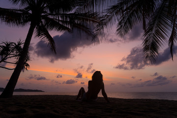 Woman on the beach at sunset under the coconut trees