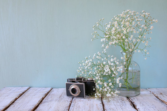 fresh white flowers and old camera over wooden table.