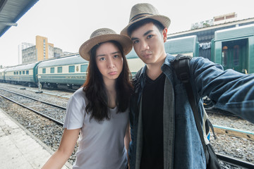 Asian young couple having fun in train station taking selfie
