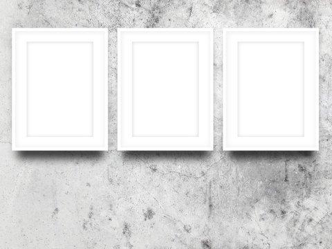 Close-up of three white picture frames on dirty concrete wall background