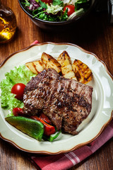 Portions of grilled beef steak with grilled potatoes and paprika