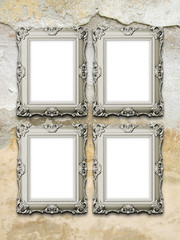 Close-up of four brown baroque picture frames on weathered concrete wall background