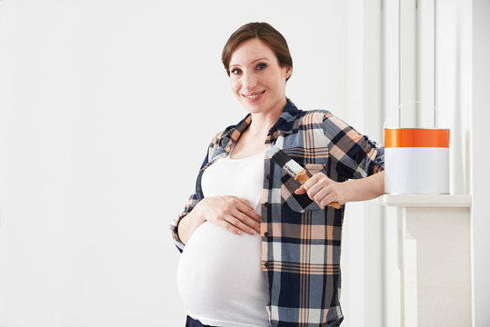 Portrait Of Pregnant Woman Decorating Nursery