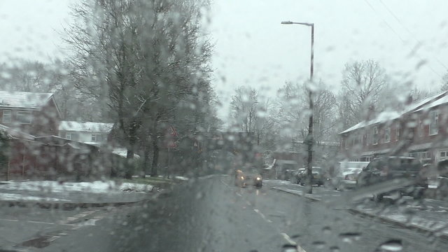 Bad weather commuting conditions in winter.Car driver's windscreen view of the road and traffic driving in sleet snow in town.