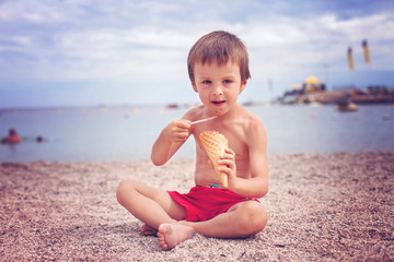 Fototapeta na wymiar Sweet little child, boy, eating ice cream on the beach