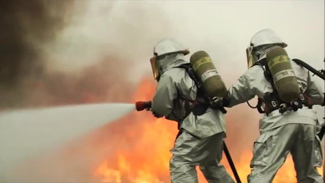 Firefighters battle a raging chemical fire in a simulated airplane crash.