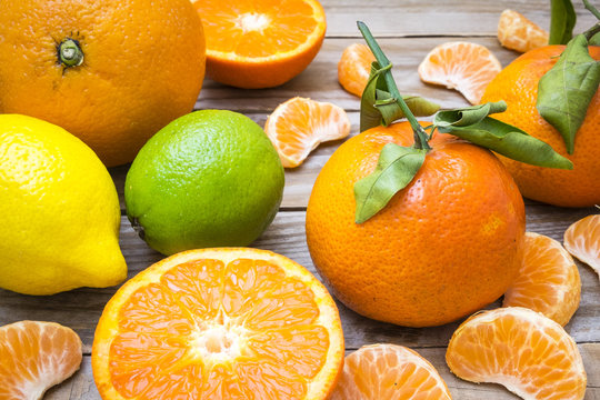 several mature citrus on a wooden table - tangerine, orange, lemon and lime
