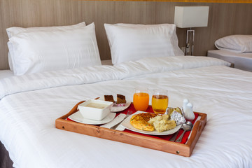 Breakfast set  in wooden tray serving on bed