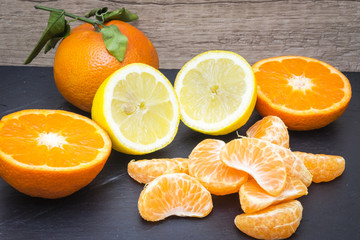 several mature citrus on a wooden table on a blackboard - lemon and tangerine

