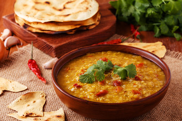 .Thick indian red lentil soup with cilantro served with indian f